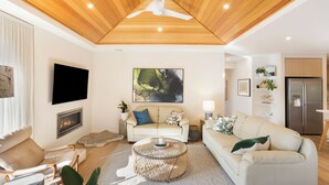 Una sala de estar moderna con chimenea, dos sofás, una mesa de centro y una televisión.