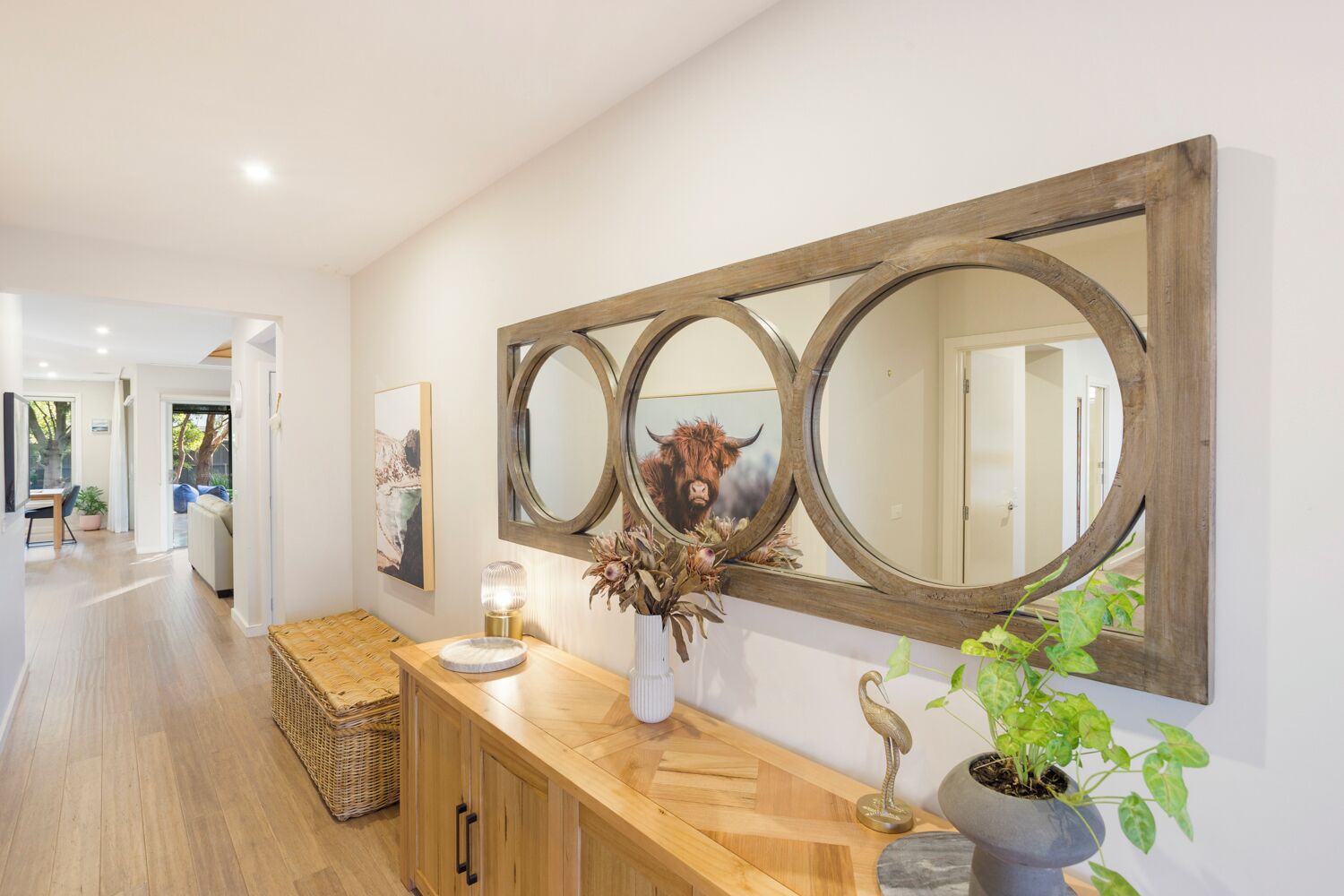A hallway with a wooden console table, a large mirror, and a potted plant.