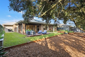 A house with a covered patio, a lawn, and a garden area.