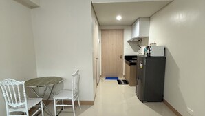 Habitació petita i senzilla amb taula de dinar, dues cadires, nevera i porta de fusta.