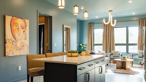 Een moderne keuken met een centraal eiland, hanglampen en een groot raam met gordijnen.
