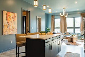 A modern kitchen with a central island, pendant lighting, and a large window with curtains. - The Golden Hour Getaway | Rooftop Deck & POOL! (Nashville)