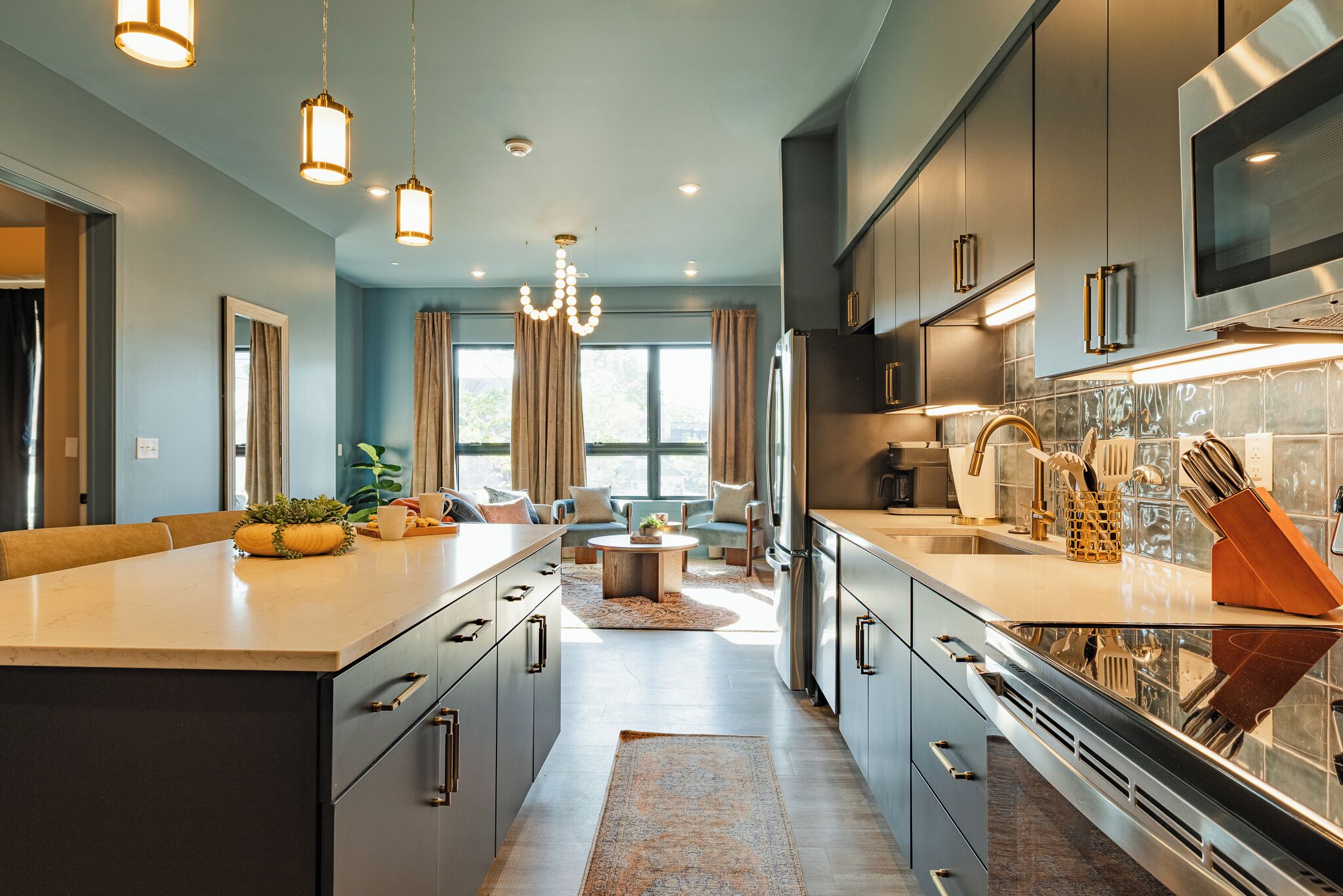 Una cocina moderna con una isla grande, electrodomésticos de acero inoxidable y un comedor con sofá y mesa de centro.