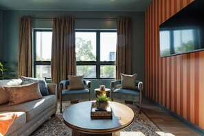 A modern living room with a sofa, two armchairs, a coffee table, and a large window with curtains. - The Golden Hour Getaway | Rooftop Deck & POOL! (Nashville)