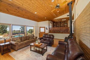 A spacious living room with a wooden ceiling, leather sofas, a coffee table, and a fireplace. - Private Hilltop Cabin Near Yosemite, California (Mariposa)