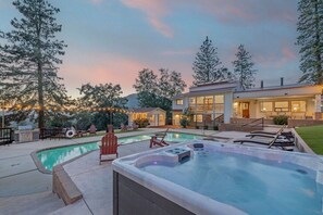 Propiedad residencial con piscina, jacuzzi y zona de estar al aire libre.