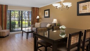 A dining area with a glass table, chairs, a sofa, and a view through large windows. - Legacy Vacation Club Resort 3 BR 2 BA Condo (Kissimmee)