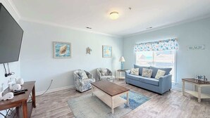 A living room with a sofa, armchair, coffee table, and a television. - Beautiful 7BR Beach House, Pool, Walk to Beach (North Myrtle Beach)