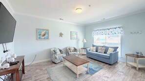 Ein Wohnzimmer mit Sofa, Sesseln, Couchtisch und Fernseher.