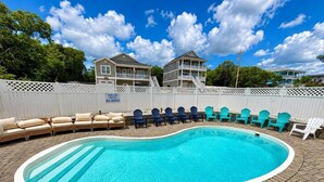 A swimming pool with lounge chairs and a deck, surrounded by a white fence, under a clear sky. - Beautiful 7BR Beach House, Pool, Walk to Beach (North Myrtle Beach)