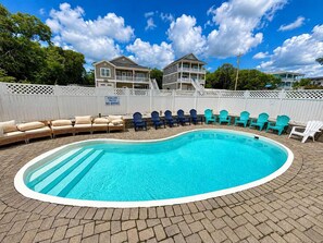 A swimming pool with lounge chairs and a deck, surrounded by a white fence, under a clear sky. - Beautiful 7BR Beach House • Pool • Walk to Beach (North Myrtle Beach)