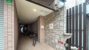 Un couloir doté d’un sol carrelé, d’un mur en pierre et d’une grille métallique.