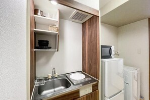 Eine kleine Küchenzeile mit Spüle, Mikrowelle und kleinem Kühlschrank.