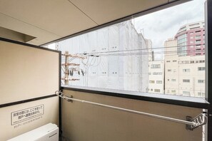 Ein Fenster mit einem Metallgeländer, einem Schild in Japanisch und Blick auf Gebäude.