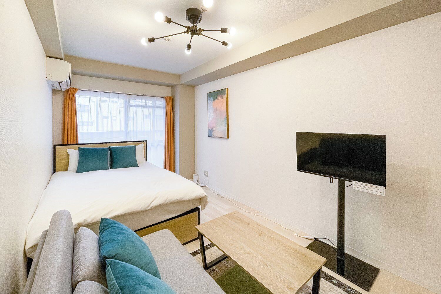 Ein Hotelzimmer mit Bett, Fernseher, Sofa und Deckenventilator.