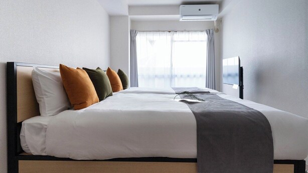 Une chambre d’hôtel avec un lit, des oreillers, une télévision et une fenêtre avec des rideaux.