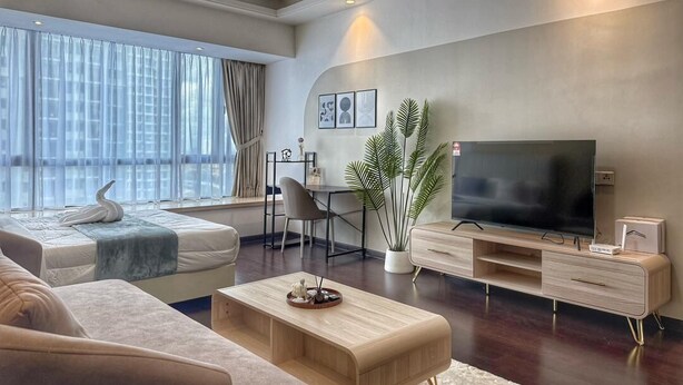 Una sala moderna con sofá, una mesa de centro, televisor, planta y comedor.