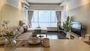 Una sala de estar moderna con un sofá, una mesa de centro con un florero, un televisor y un escritorio con una silla.
