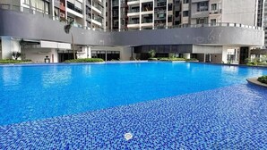Una piscina con mosaicos azules, rodeada por un edificio moderno con varios balcones.