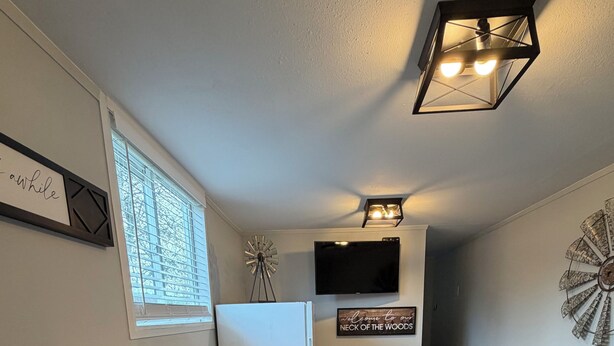 A compact kitchen with a refrigerator, coffee maker, microwave, and a coffee grinder on the counter.