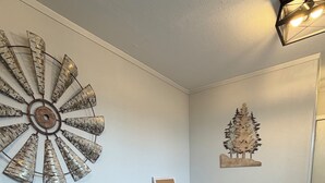 A dining area with a wooden table and benches, a decorative wall piece, and a small wooden tree decoration.
