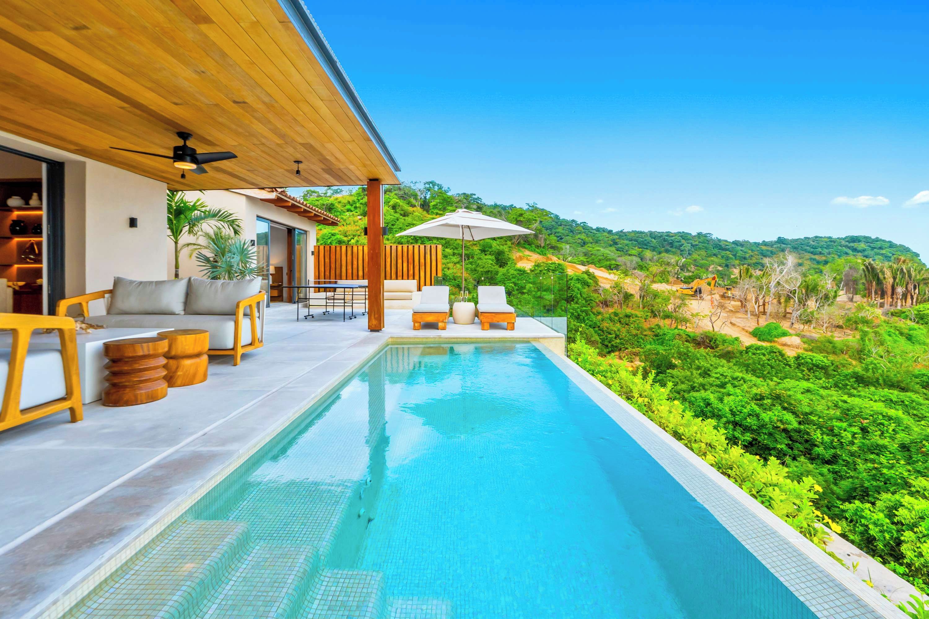 A modern outdoor pool area with a view of a lush green landscape.