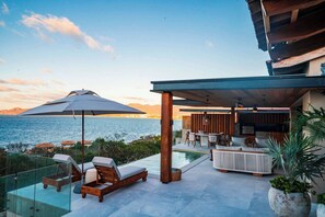 A modern outdoor seating area with a pool, lounge chairs, and a dining table. - Luxury Iyari Villa Inside Punta Mita Ocean View (Corral del Risco)