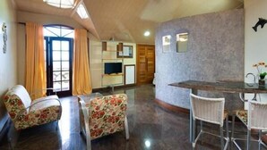 A room with a dining table, chairs, a television, and a large window with curtains. - Hotel privê do Atalaia  (Salinópolis)