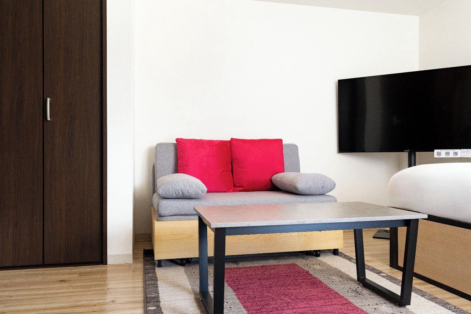 Una habitación con sofá, mesa, televisor y armario.