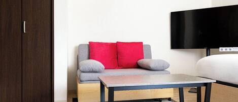 Una habitación con sofá, mesa, televisor y armario.