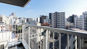 Paesaggio urbano con edifici moderni, cielo sereno e ringhiera da balcone.