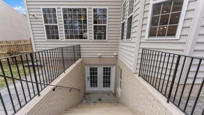 A staircase leading to a door with a glass panel, flanked by two black metal railings, and a brick wall on one side. -  Spacious Private Suite in Gainesville • Separate Entrance • WiFi • Washer/Dryer (Gainesville)