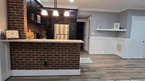A kitchen with a brick accent wall, stainless steel appliances, and a white countertop. -  Spacious Private Suite in Gainesville • Separate Entrance • WiFi • Washer/Dryer (Gainesville)