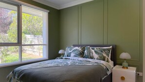 Une chambre à coucher avec un lit, des tables de chevet et une fenêtre donnant sur des arbres.