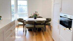 Une cuisine moderne avec une table de salle à manger ronde, six chaises, une plante en pot et un four encastré.