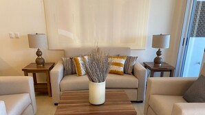 Ein Wohnzimmer mit einer Couch, zwei Beistelltischen, einem Couchtisch und einer Vase mit Ästen.