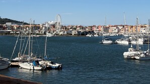 A marina with boats docked, a Ferris wheel in the background, and buildings along the waterfront.