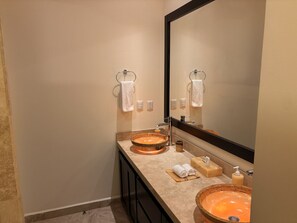 Un baño con dos lavamanos, un espejo grande y un perchero para toallas.