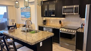 A modern kitchen with granite countertops, stainless steel appliances, and black cabinetry. - One Bedroom Oceanfront - Puerto Escondido 1423 (Bajos de Chila)