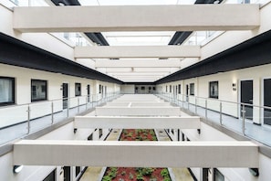 A modern hotel interior with a central atrium, multiple floors, and a central garden area. - Stylish 1BR Flat in Hull City Centre (Hull)