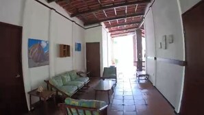 A hallway with a tiled floor, a green sofa, a small table, and a chair. - In Front of the Beach! Spacious 4-bedroom villa in charming Sonsonate with AC. (Sonsonate)