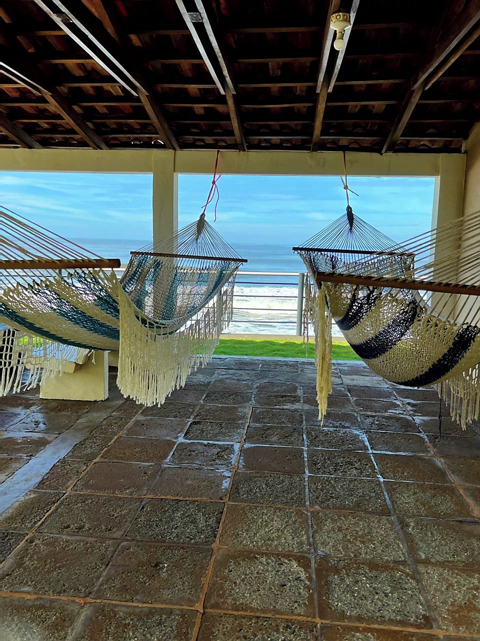 Un espacio al aire libre techado con hamacas y vistas al mar.