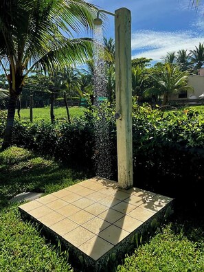 A water feature with a square base and a vertical spout, surrounded by greenery and palm trees. - In Front of the Beach! Spacious 4-bedroom villa in charming Sonsonate with AC. (Sonsonate)