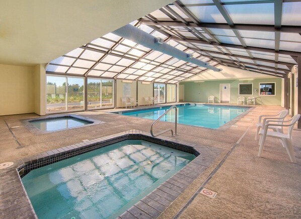 Ein Hallenbad mit Glasdecke, zwei Whirlpools und Blick ins Freie.