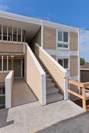 Ein mehrstöckiges Gebäude mit einer Treppe, einem überdachten Außenbereich und einer Ziegel-Fassade.