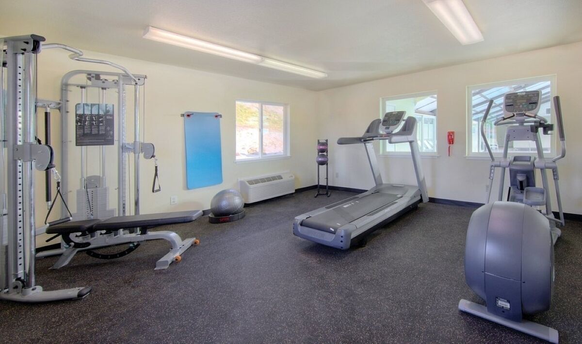 Et fitnesscenter med løbebånd, crosstrainere og styrketræningsudstyr.