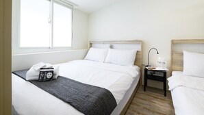 Habitación de hotel con cama, mesita de noche, ventana y estante en la pared.