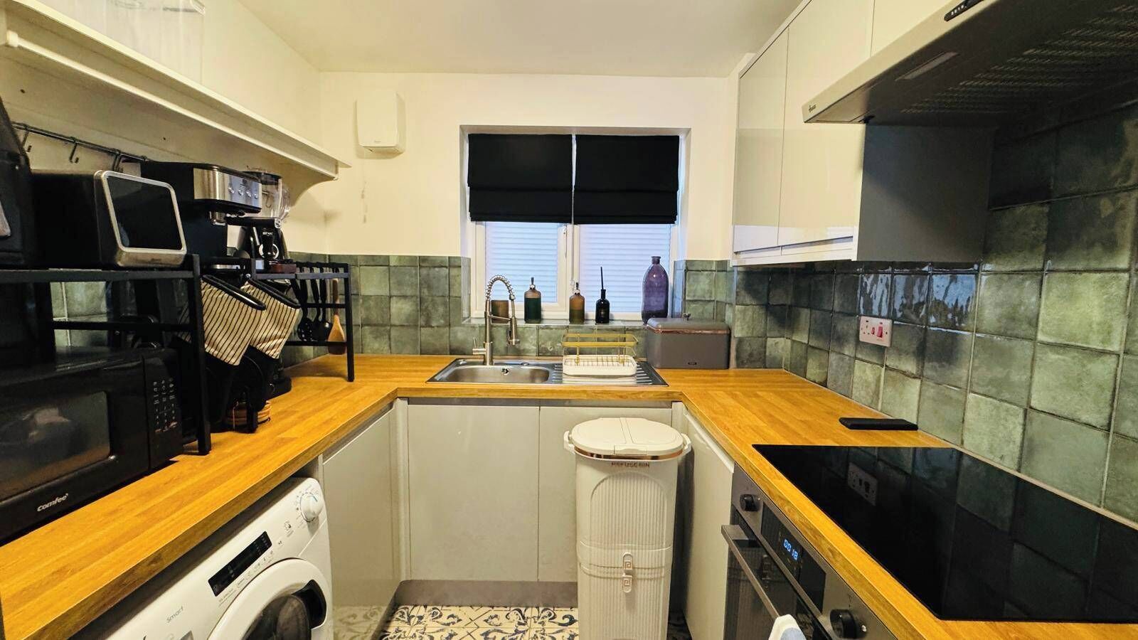 A compact kitchen with a washing machine, a microwave, a coffee maker, and a sink.