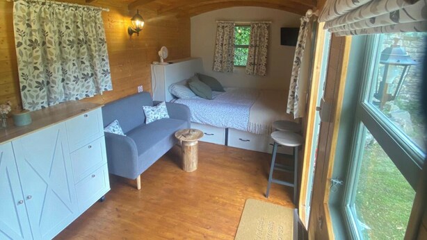 L’intérieur d’un chalet confortable, avec un canapé, un lit, une petite table et une fenêtre.