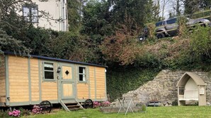 Une petite cabane en bois avec une porte, des fenêtres et une rampe menant à un porche.